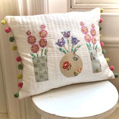 a white chair with a pillow decorated with flowers and pom - poms on it