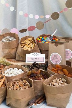 a table topped with brown paper bags filled with different types of snacks and candies