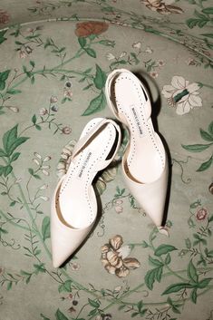 two pairs of white shoes sitting on top of a floral print chair cushioned area