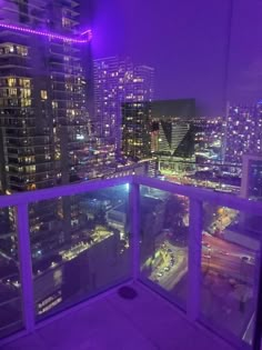 a balcony with city lights in the background and purple lighting on the glass railings