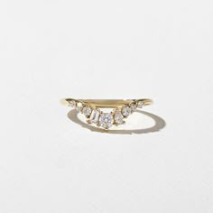 a gold ring with three small diamonds on the front and back, sitting on a white surface