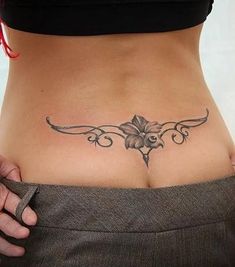 a woman's stomach with a flower tattoo on her belly and the bottom part of her lower back