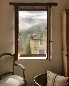 an open window in a room with a chair next to it and a basket on the floor