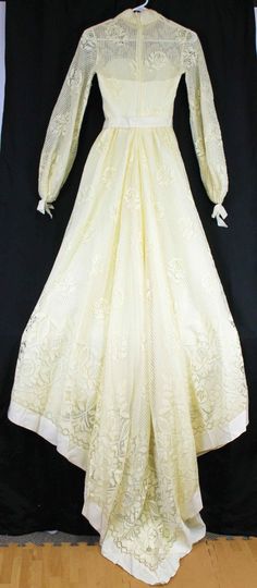 "Ivory dress, heavy-weight polyester lined with a cotton type of lace Grosgrain ribbon trim, sweetheart neckline under the lace. Ribbon around waist with long ribbon strands hanging from waist. Long sleeves with ribbon gathered cuffs. High neckline with dainty flower embroidered trim Train comes to a V like point On left-back arm seam, there is some lace stitching that has loose strands. Metal zipper closure No tags anywhere, appears to be handmade Woman's Size 6/8 based on measurements Approx m Fitted Contrast Lace Dress For Wedding Night, Ceremony Lace Dress With Sweetheart Neckline, Lace Dresses With Sweetheart Neckline For Ceremony, Lace Gown With Sweetheart Neckline For Ceremony, Sweetheart Neckline Lace Dress For Ceremonies, Lace Gown For Ceremony With Sweetheart Neckline, Fitted Lace Dress With Contrast Lace For Wedding, Fitted Contrast Lace Wedding Dress, Vintage White Dress With Sweetheart Neckline