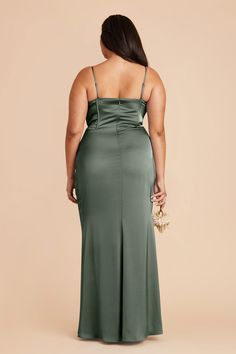 a woman in a green dress with her back turned to the camera, looking down