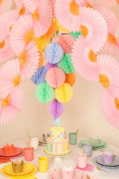 a table topped with a cake and lots of paper umbrellas hanging from the ceiling