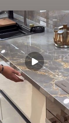 a person standing in front of a kitchen counter with marble on the top and bottom