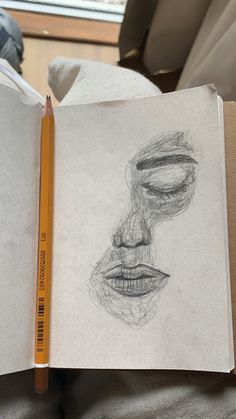 an open book with a drawing of a man's face on the page and pencil