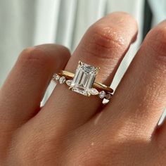 a woman's hand with a ring on it and an emerald stone in the middle