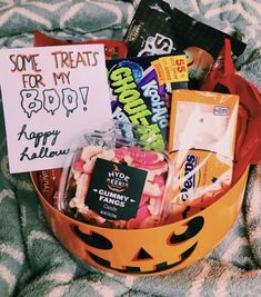 a halloween treat basket with candy, candies and greeting cards in it on a blanket