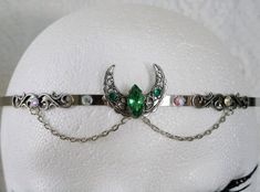 Crescent Moon Circlet This beautiful circlet has a sterling silver plated filigree crescent moon with emerald green faceted glass setting, sterling silver plated filigree accents, rhinestones and metal chain. Adjustable. Silver Fantasy Costume Jewelry, Silver Fantasy Crown-shaped Jewelry, Silver Crown Fantasy Jewelry, Fantasy Silver Crown Jewelry, Fantasy Crown-shaped Jewelry Gift, Fantasy Crown Shape Jewelry For Gifts, Fantasy Crown Jewelry For Gifts, Bohemian Crown Shaped Jewelry Gift, Handmade Bohemian Costume Jewelry