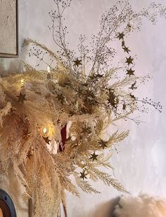 a vase filled with dried flowers on top of a table next to a clock and wall