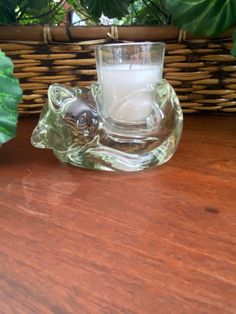 a glass candle holder sitting on top of a wooden table next to a potted plant