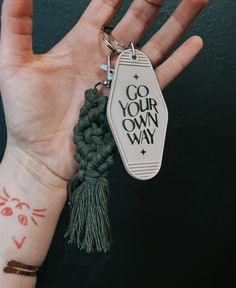 a person's hand with a tattoo on it and a tag that says go your own way