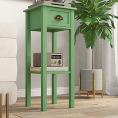 a green end table with a radio on top and a plant in the corner next to it