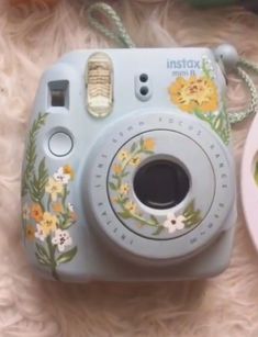 an instax camera sitting on top of a white rug next to a plate