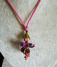 "The flower is made of components from the Miriam Haskle Estate via Jill MacKay.  It was bare metal and I painted it.  Prior to wearing it, it should be coated with a protective seal.  The rope is a rosey pink suede and is adjustable.  The pendant is about 2\" long and the rope can be as long as 32\"." Adjustable Artistic Flower Jewelry, Artistic Adjustable Flower Jewelry, Bohemian Pink Necklace With Flower Charm, Pink Bohemian Necklace With Flower Charm, Pink Adjustable Bohemian Flower Necklace, Adjustable Pink Bohemian Flower Necklace, Bohemian Adjustable Pink Flower Necklace, Artistic Pink Flower Jewelry, Bohemian Hand Painted Flower Jewelry