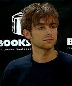 a man is standing in front of a book store sign and looking at the camera