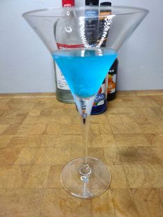 a blue drink in a martini glass on a table