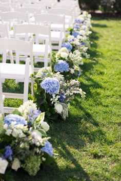 rows of white chairs with blue and white flowers lining the aisle at an outdoor ceremony