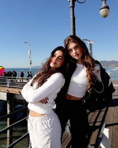 two women standing next to each other on a pier