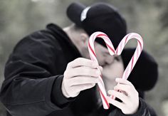 a man holding a candy cane in front of his face and making a heart shape