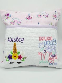 two pillows with unicorns and flowers on them, one has a name written on it