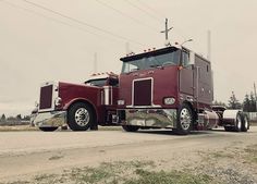 a red semi truck driving down a rural road