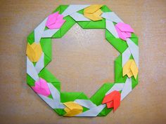 an origami wreath made out of paper with yellow, pink and green leaves