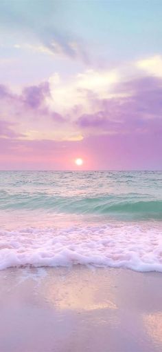 the sun is setting over the ocean with waves coming in to shore and pink clouds