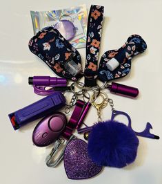 various items are arranged on a table with a purple keychain and blue pom - pom