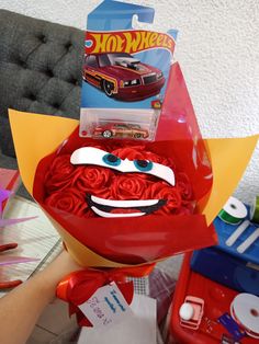 a hand holding a red rose bouquet with cars on it