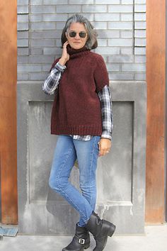 a woman standing in front of a brick wall talking on a cell phone while wearing boots