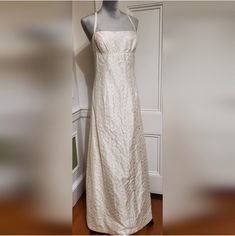 a white dress hanging on a mannequin in a room next to a door