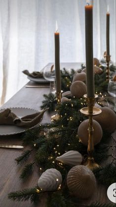 a long table with candles, plates and napkins on it is decorated for christmas