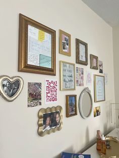 a wall with many different pictures and frames hanging on it's side, along with other items