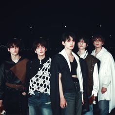 five young men standing together in front of a dark background