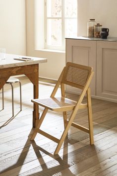 a wooden chair sitting on top of a hard wood floor next to a kitchen counter