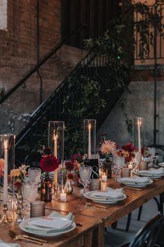 the table is set with candles, plates and flowers in vases on it's sides