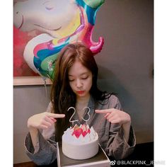 a woman pointing at a birthday cake in a box