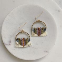 a pair of beaded hoop earrings on a marble plate