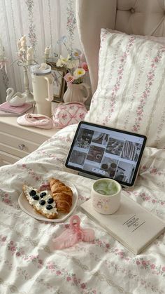 an open laptop computer sitting on top of a bed next to a plate of food