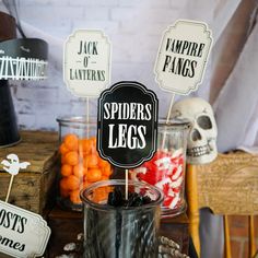 there are halloween decorations on the table with candles and signs in front of them that read, spider legs