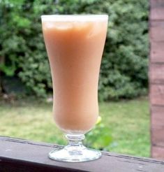 a tall glass filled with liquid sitting on top of a window sill