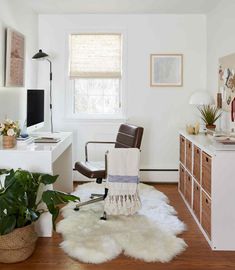 a white room with a chair, desk and plants