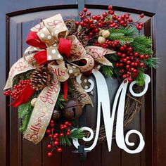 a christmas wreath with red berries, pine cones and bells on a door handle that says merry