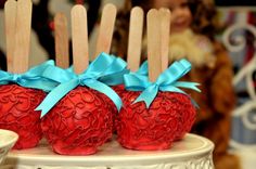 two red apples with wooden sticks sticking out of them sitting on top of a cake plate