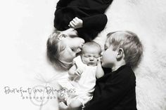 three young children laying on top of each other with their hands around the baby's head