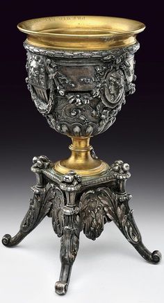 an ornate silver and gold urn sitting on top of a table