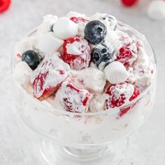 a bowl filled with fruit and marshmallows on top of a white table